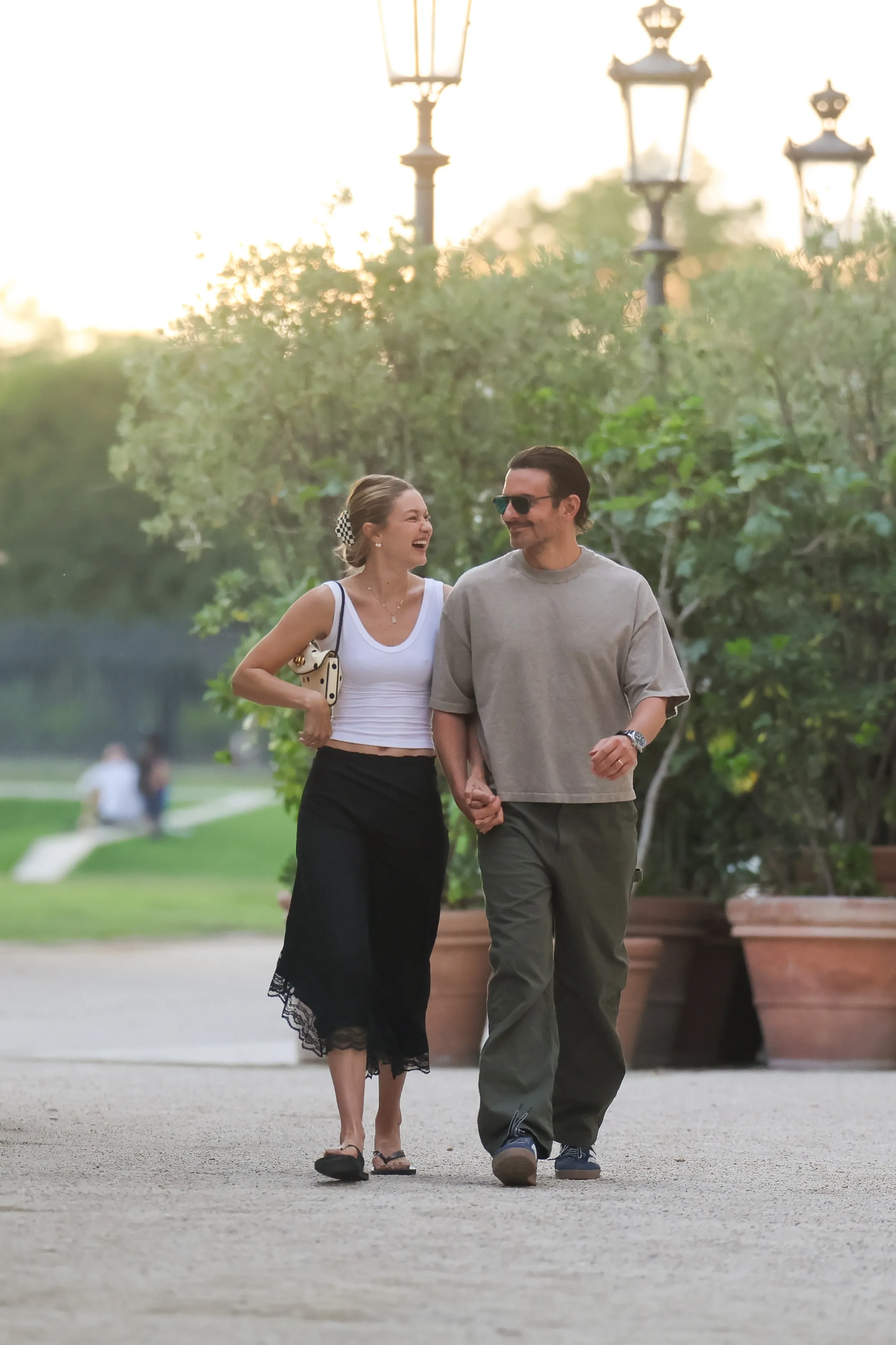 Bradley Cooper and Gigi Hadid holding hands and walking outdoors.