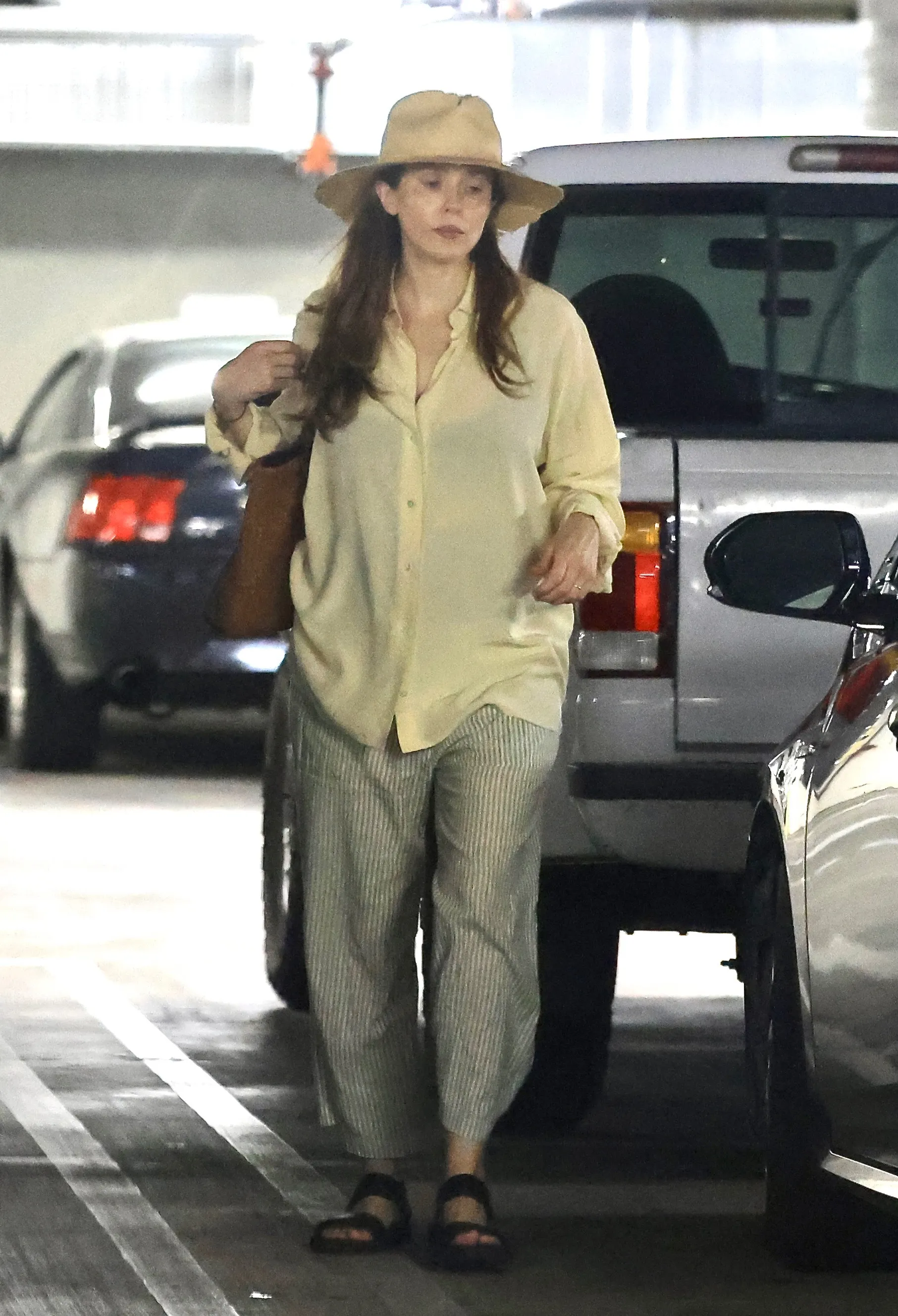 Elizabeth Olsen grocery shopping at Whole Foods in Sherman Oaks, wearing a yellow blouse, pinstriped wide-leg pants, black sandals, and a straw hat.