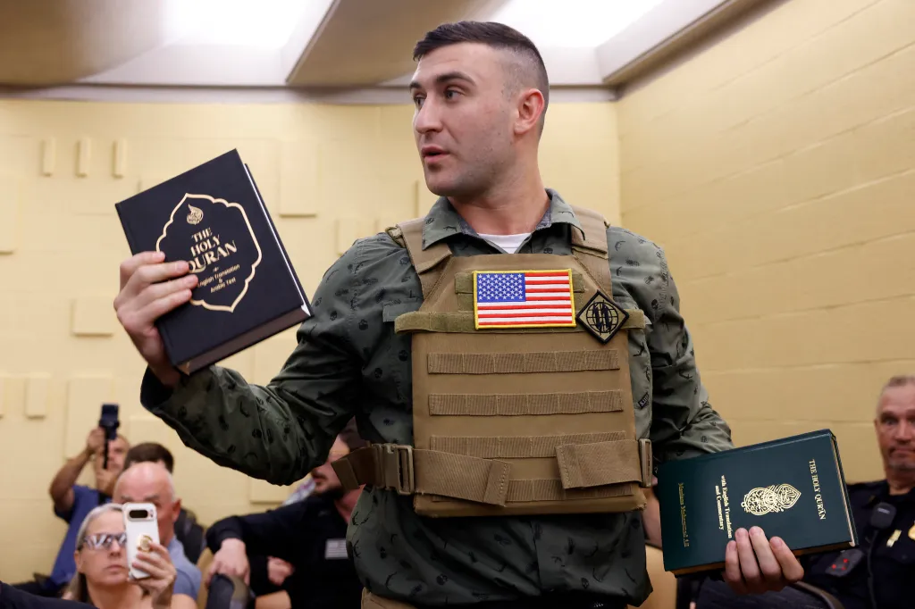 Far-right activist Jake Lang holds copies of the Quran after addressing a meeting of the Dearborn City Council in Dearborn, Michigan, on Tuesday, August 18, 2026.