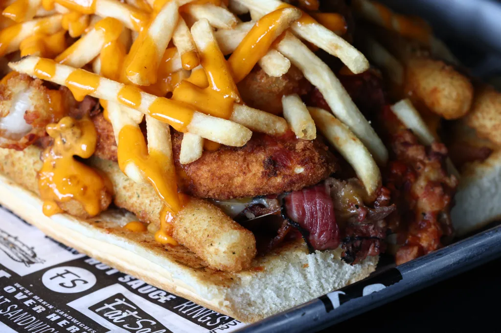 Fat Sal's Big Fat Fatty sandwich filled with various foods, topped with fries and a sauce.