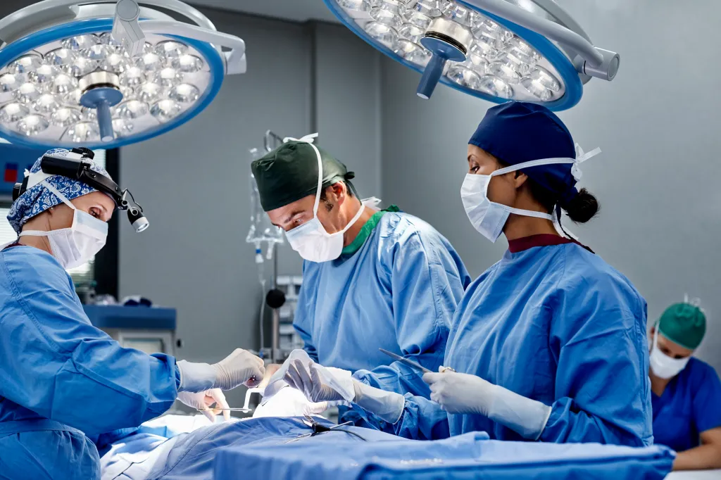 A female surgeon operating on a patient alongside medical professionals in an emergency room.
