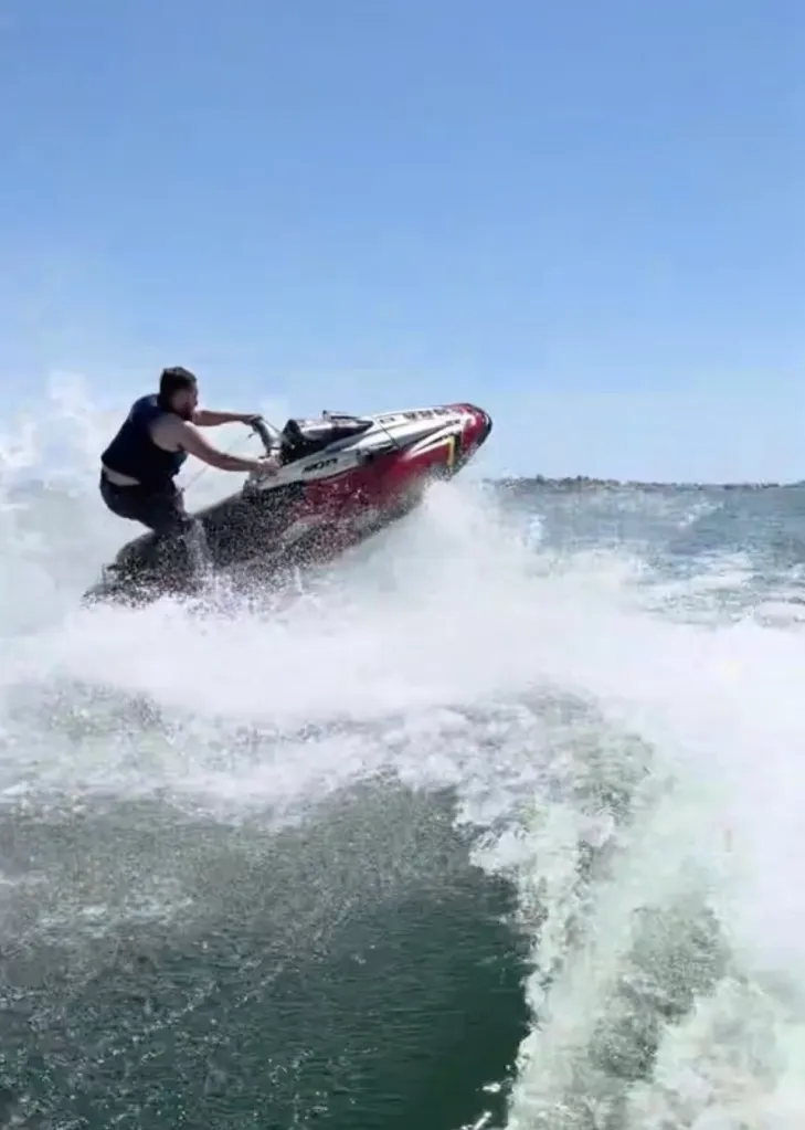 A man on a red and white jet ski in the water.