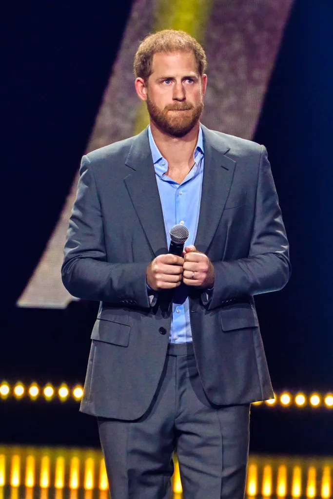 Prince Harry standing on stage holding a microphone.