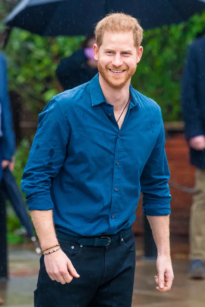 Prince Harry in a blue shirt smiling.