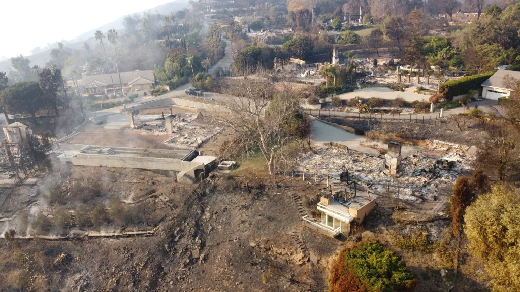 Aerial view of a Malibu home unscathed by fires surrounded by burnt-out properties.