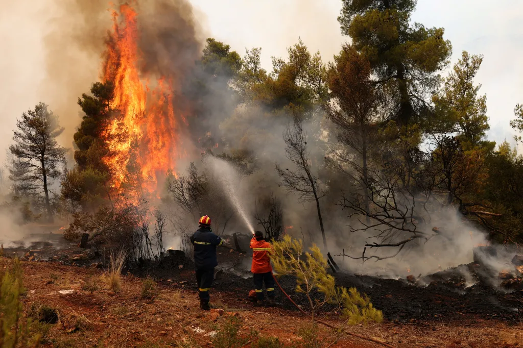 Two firefighters spray water on a raging wildfire near Agia Paraskevi, Greece.