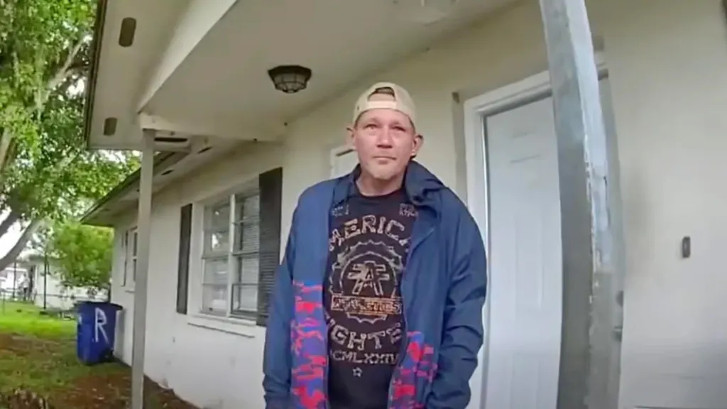 A man in a baseball cap, blue jacket, and