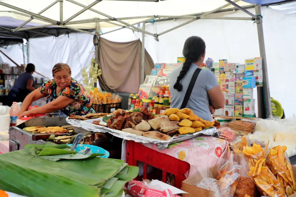 Food vendors selling traditional foods like tamales, pupusas, and fried plantains at a market on Salvador Corridor in Los Angeles.