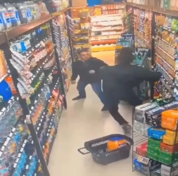 A store manager and a shoplifter confronting and shoving each other in an aisle at the Food Universe Marketplace.