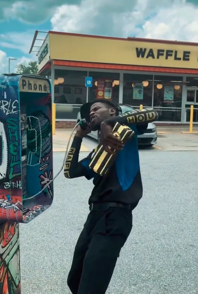 Rockstar Riley on a payphone outside a Waffle House.