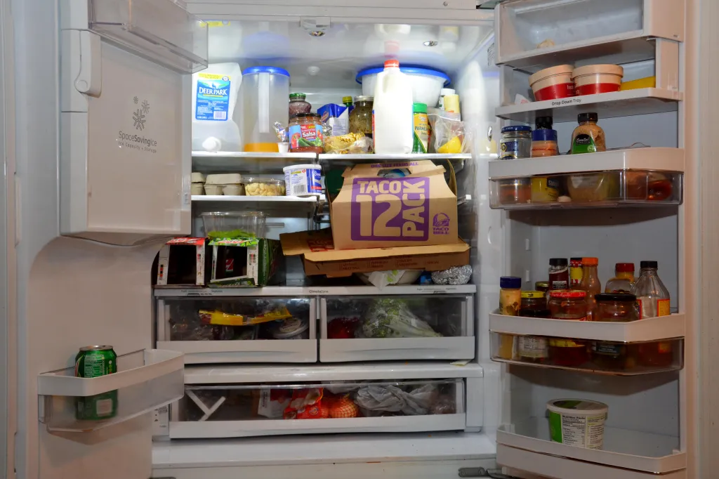 An open refrigerator filled with a mix of healthy food, junk food, and condiments.