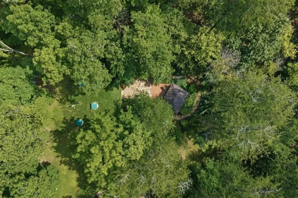 Aerial view of an earth-sheltered home nestled within a dense green forest.