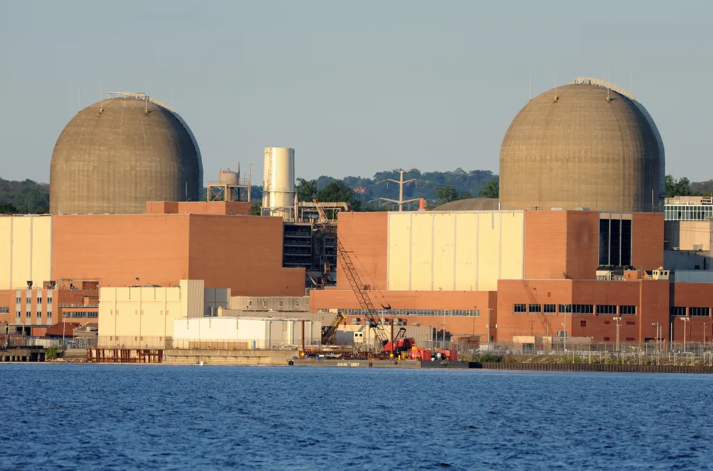 The Indian Point Nuclear Power Plant, featuring two large domed containment buildings and brick industrial structures, viewed across a body of water.
