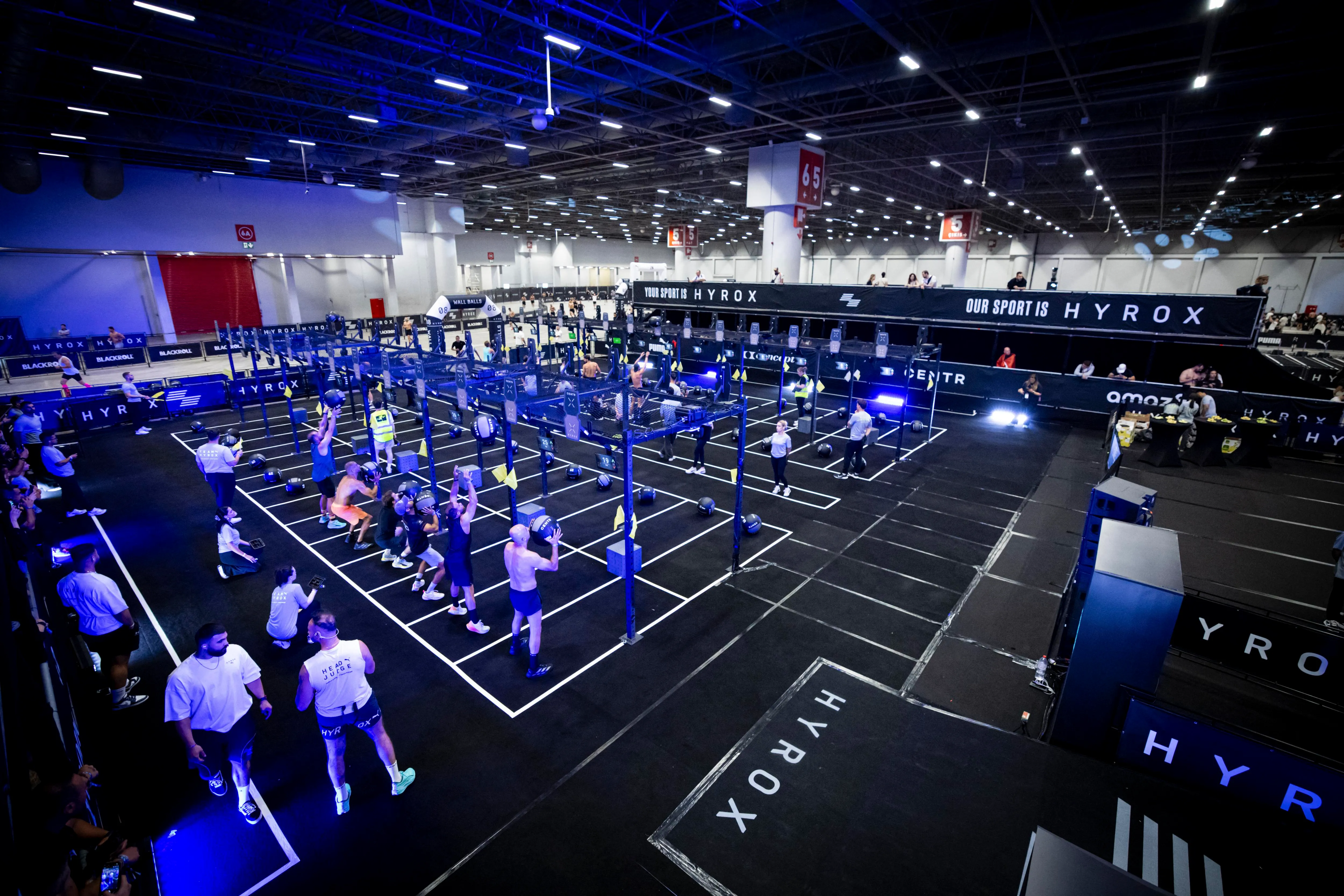 People in front of exercise stations in the gym about to perform a weighted or strength-based exercise.