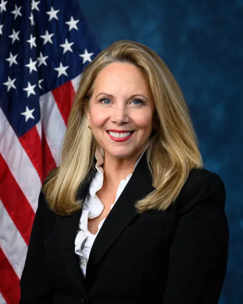 Laura Gillen smiling in front of an American flag.