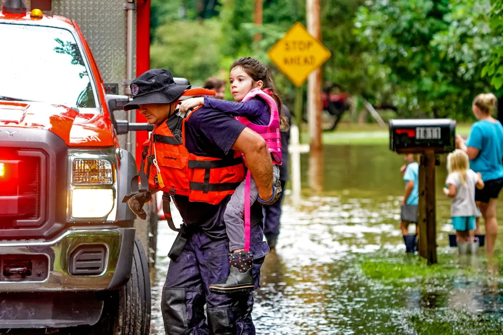 A girl is carried from flood waters by a rescuer as evacuations are underway in Ravenswood neighborhood due to flooding after days of heavy rain in Indianapolis, Indiana.
