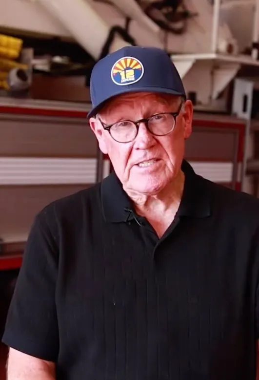 Glen Keane wearing a black polo shirt, glasses, and a blue baseball cap with an Arizona logo.