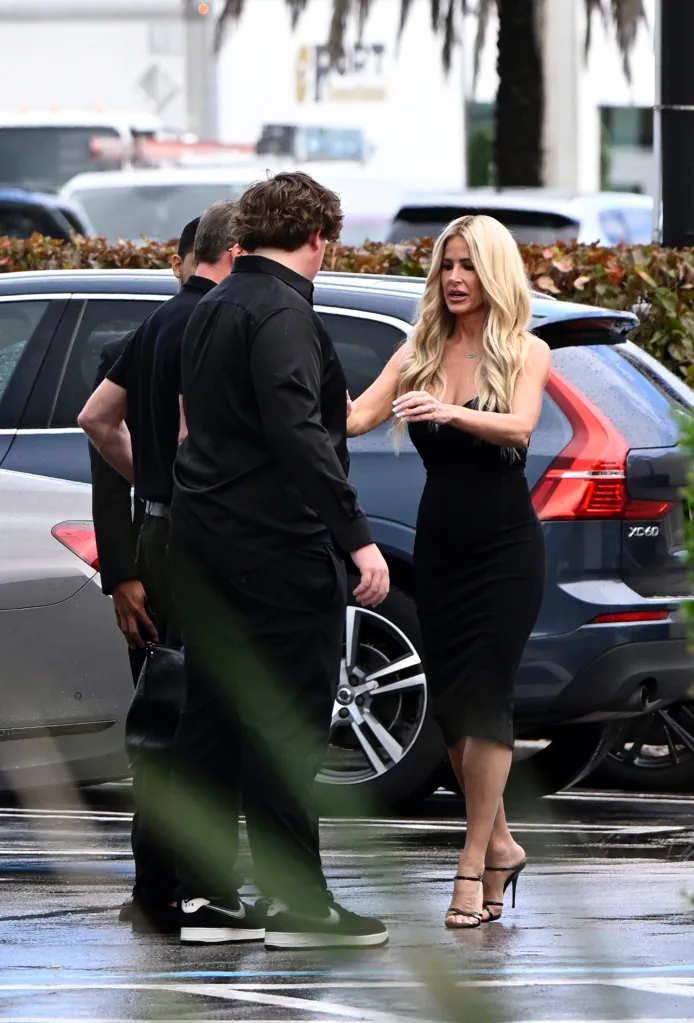 Kim Zolciak-Biermann in a black dress with two men, one of whom is her son Kash.
