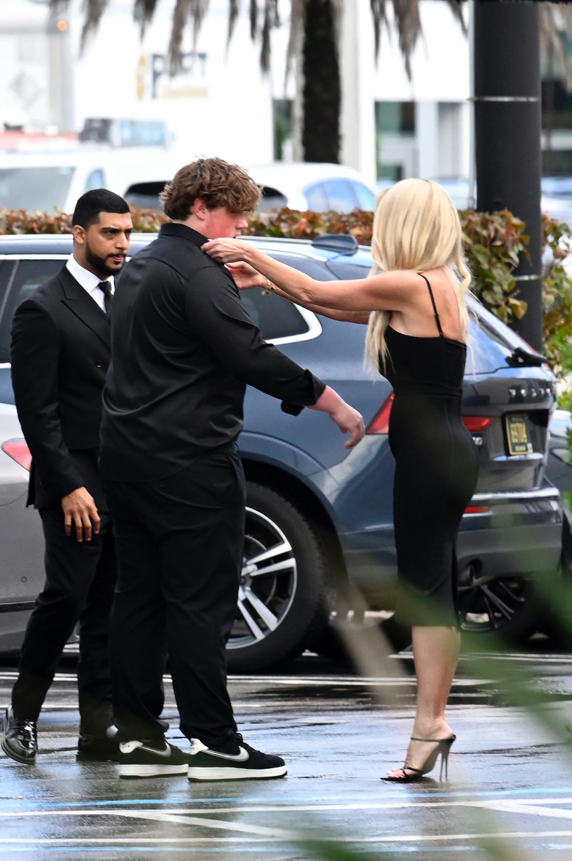 Kim Zolciak adjusts her son Kash's collar while her boyfriend Kyle Mowitz stands nearby.