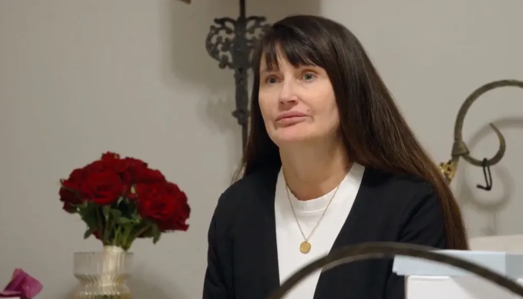 Debbie, from 90 Day Fiance, with a bouquet of red roses to her left.
