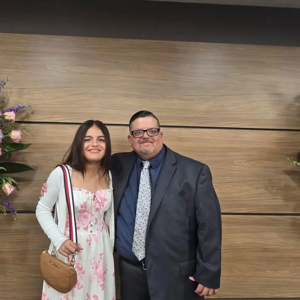 Greg Medina and his daughter, smiling while standing next to each other.
