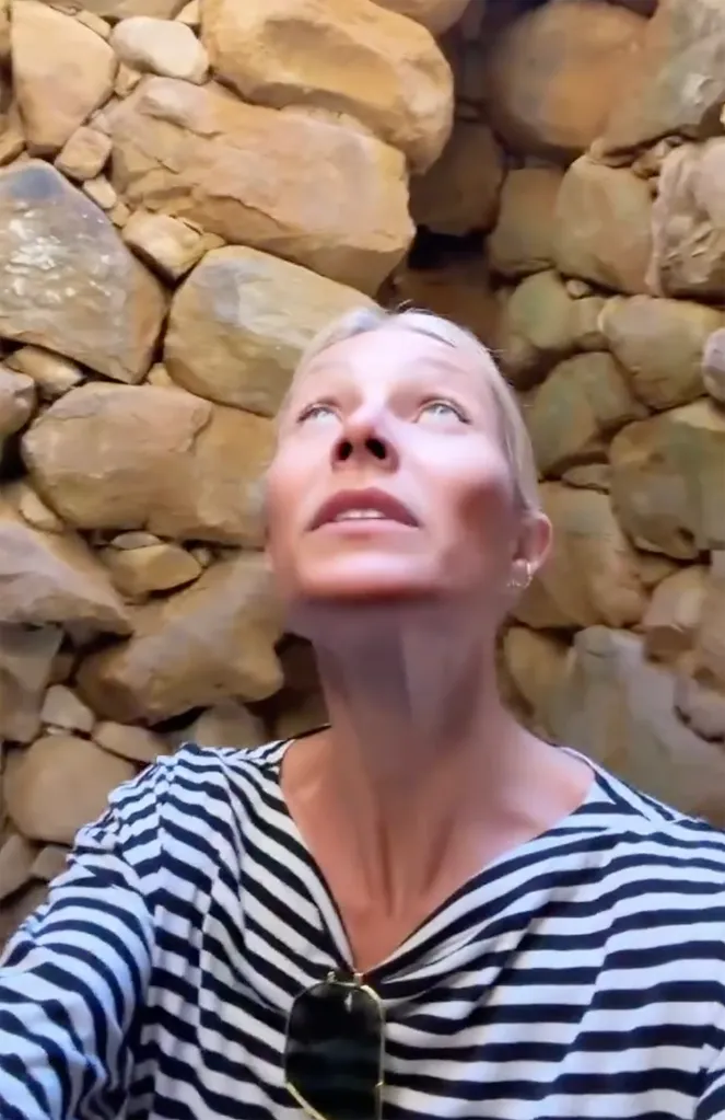 Gwyneth Paltrow looking up at a stone wall.
