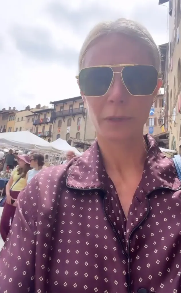 Gwyneth Paltrow in a patterned purple shirt and sunglasses outdoors.