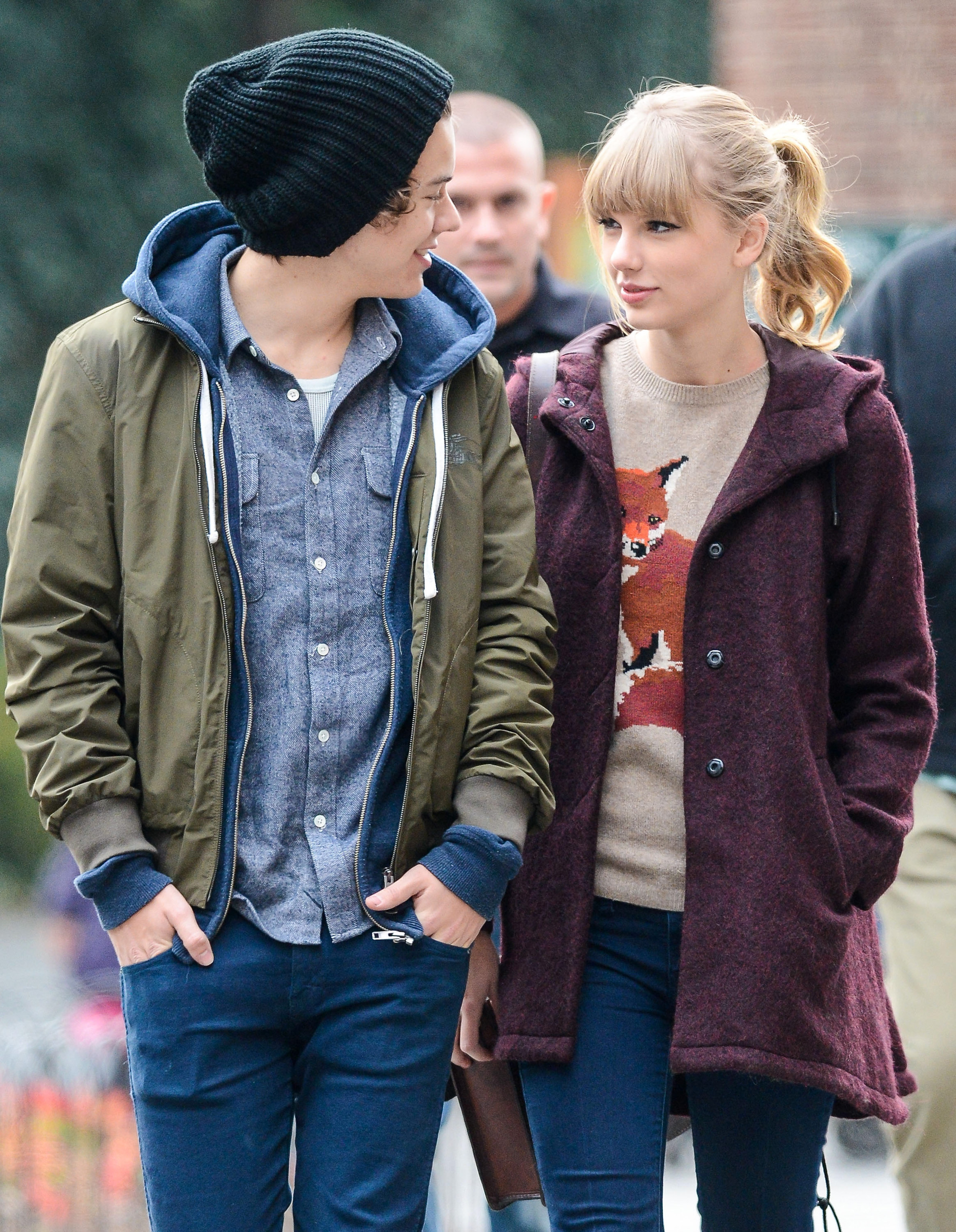 Harry Styles and Taylor Swift looking at each other while walking.