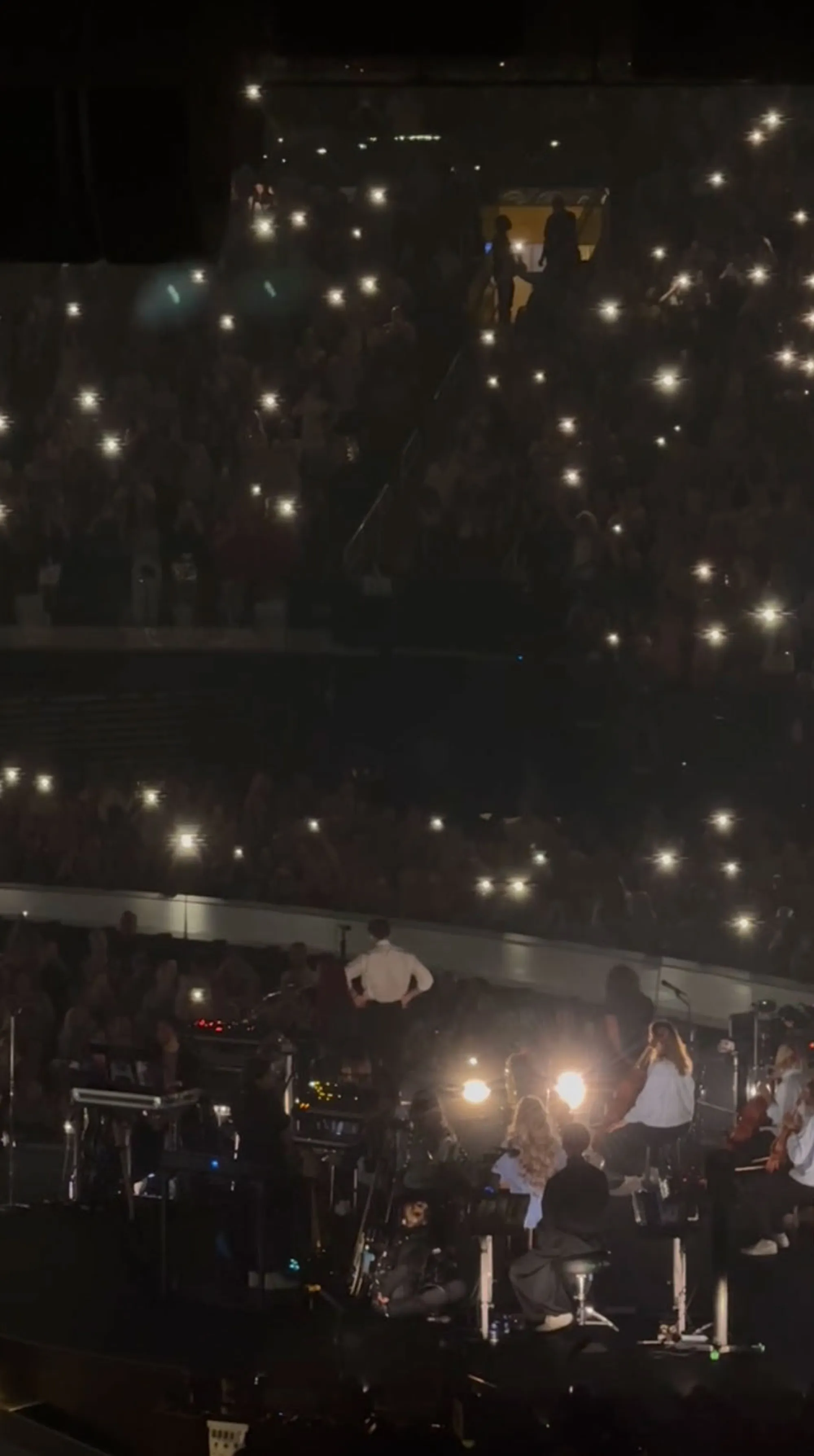 Harry Styles performing a tribute to Dolly Parton at Madison Square Garden with the audience holding up their phone lights.