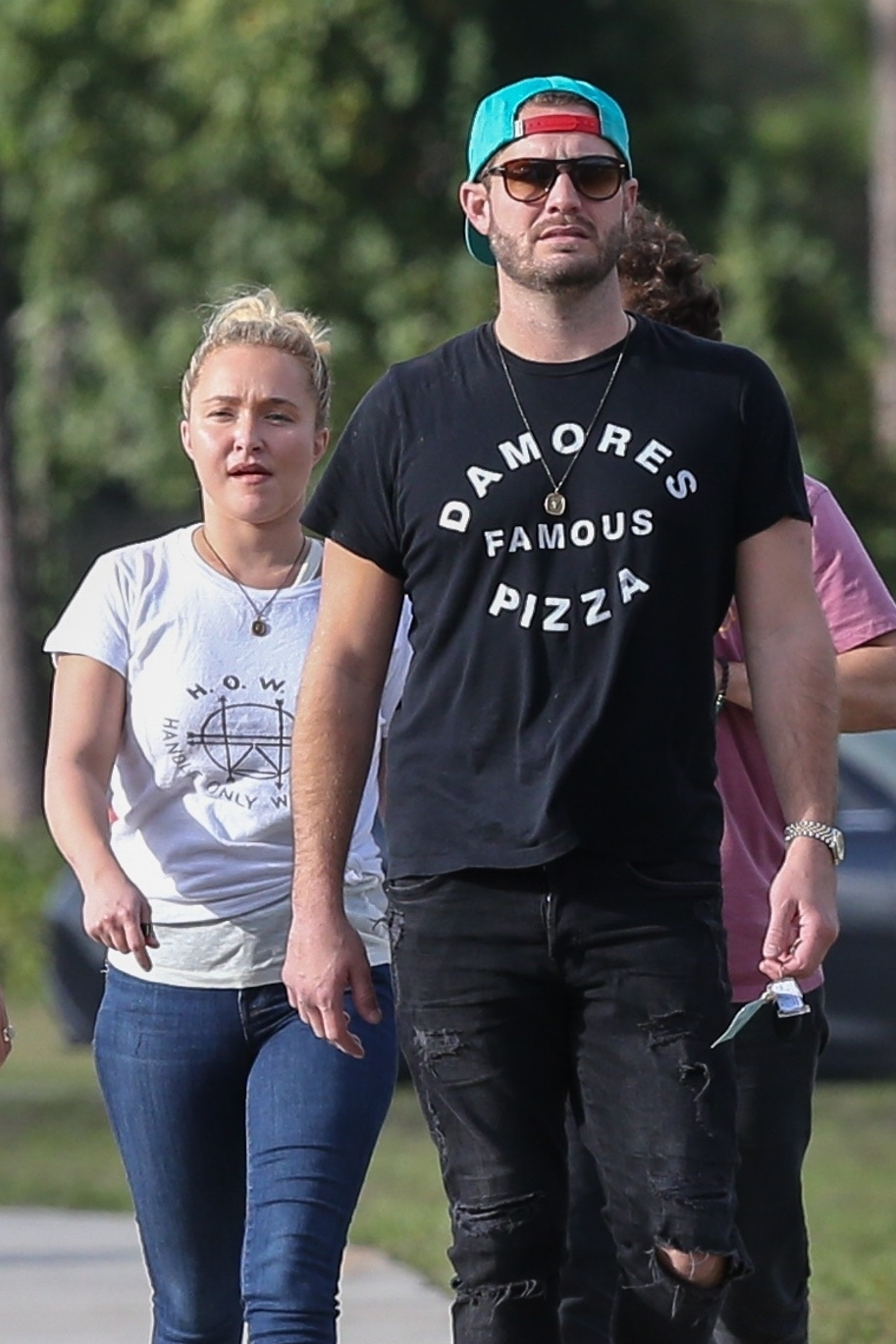 Hayden Panettiere and Brian Hickerson walk outdoors, with Hickerson wearing a teal baseball cap and sunglasses.