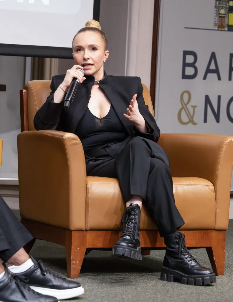 Hayden Panettiere speaking into a microphone while seated in a brown leather armchair.