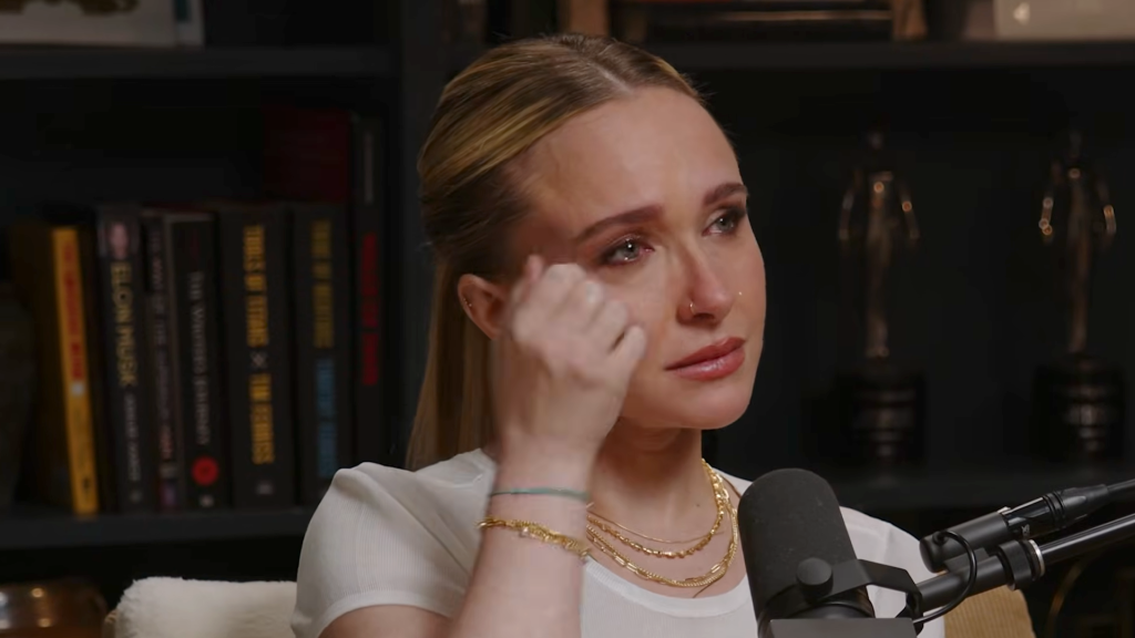 Hayden Panettiere wiping away tears while speaking into a microphone.