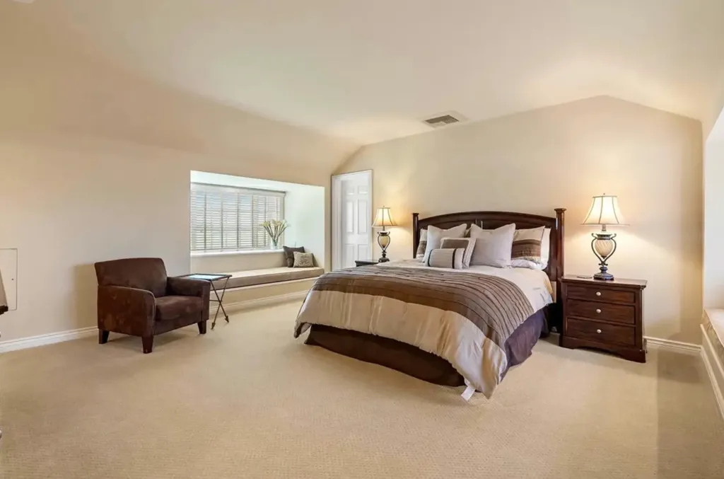 Bedroom in Alex Trebek's former 700-acre estate, Windfall Farms, with a large bed, nightstands, lamps, and a window seat.