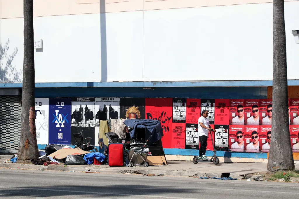 A homeless individual's belongings and a person on an electric scooter on Van Nuys Boulevard, Los Angeles.