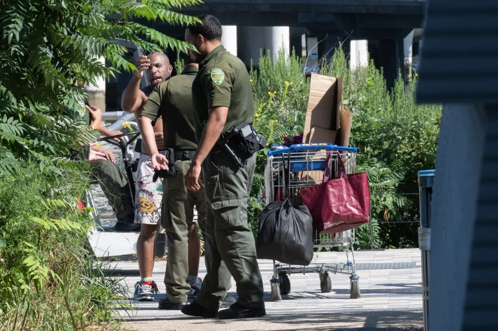Homeless people, including one man wearing a penis mask, are removed by park enforcement from Pier 53 in Hudson River Park.
