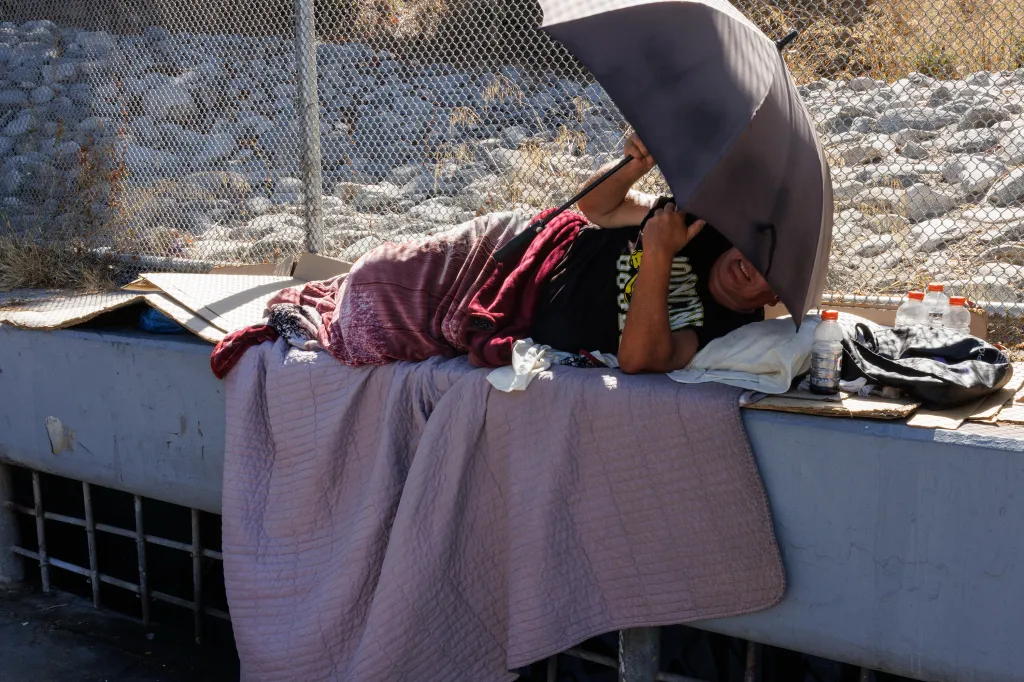 A homeless man lies on a cul-de-sac in Los Angeles, California, shading himself with an umbrella.