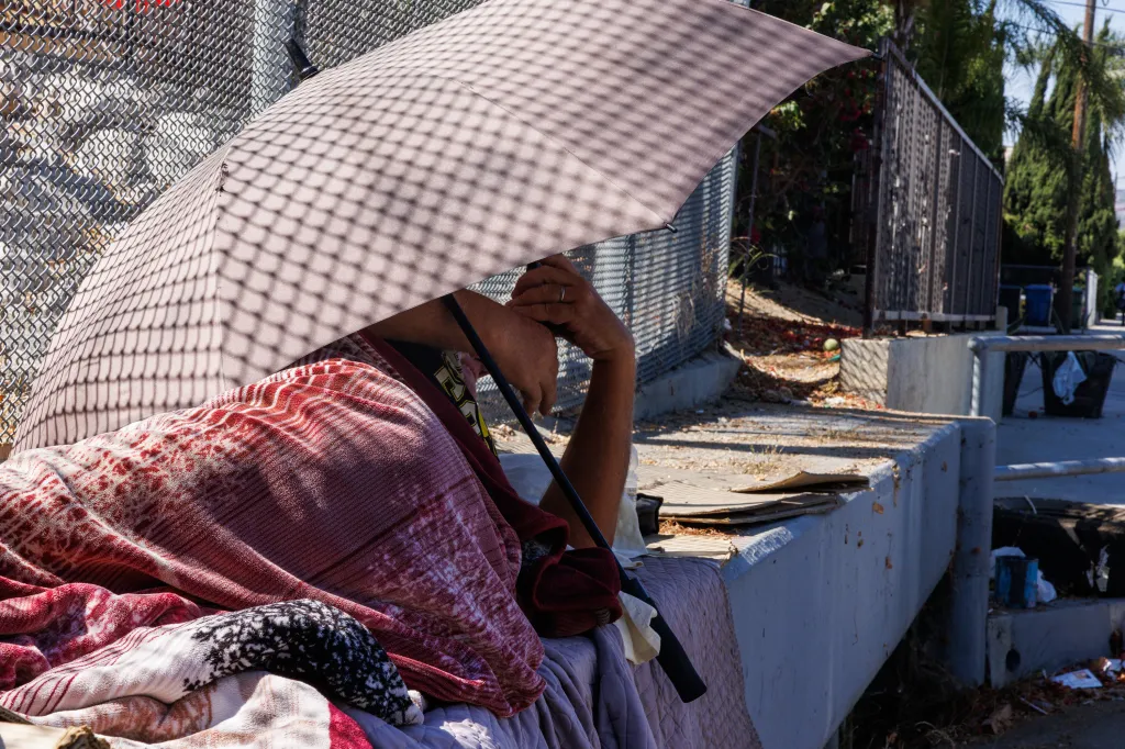A homeless person sleeps under an umbrella in a cul-de-sac.