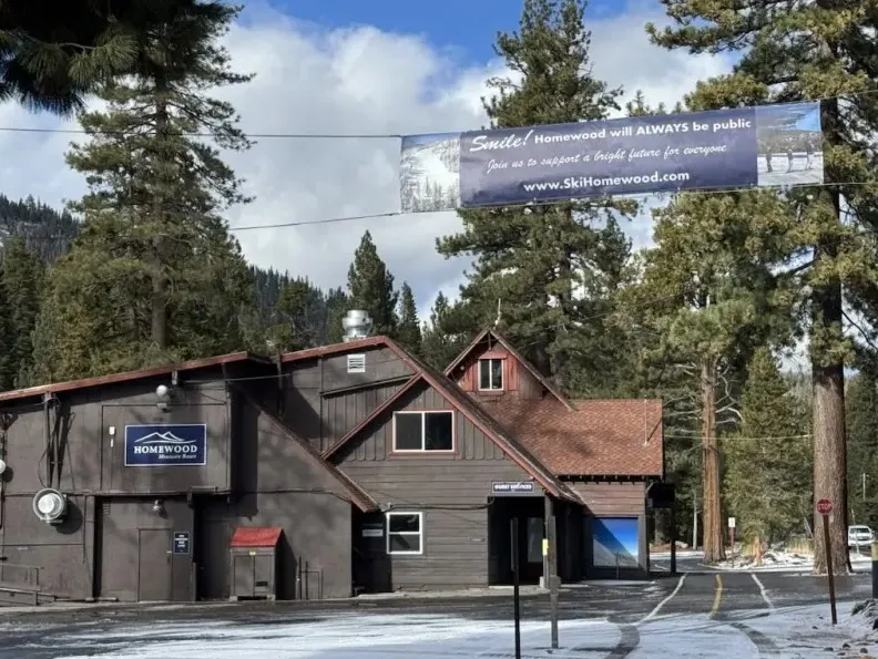A dark brown building of Homewood Mountain Resort with a banner across the road that reads 