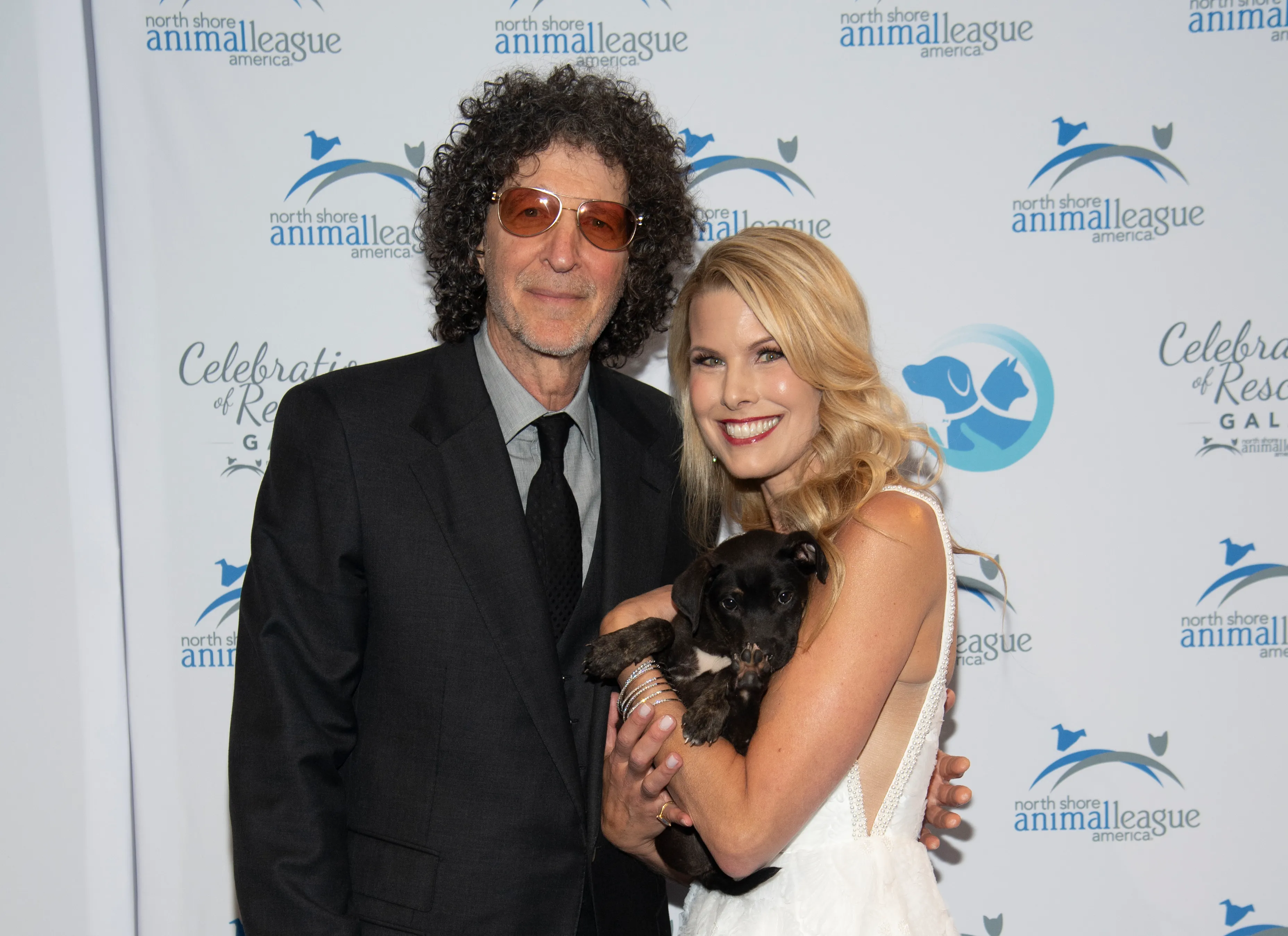 Howard Stern and Beth Ostrosky Stern hold a small dark puppy at the North Shore Animal League America Celebration of Rescue.