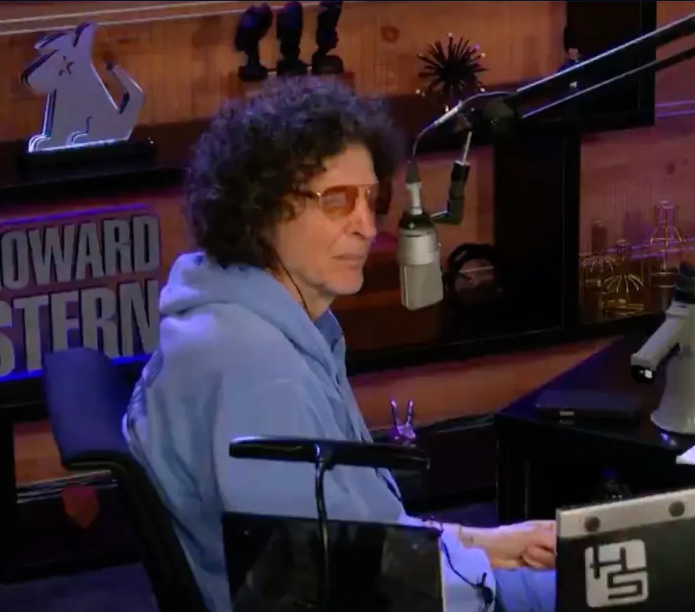 Howard Stern in a blue hoodie and orange-tinted sunglasses at his Sirius XM show.