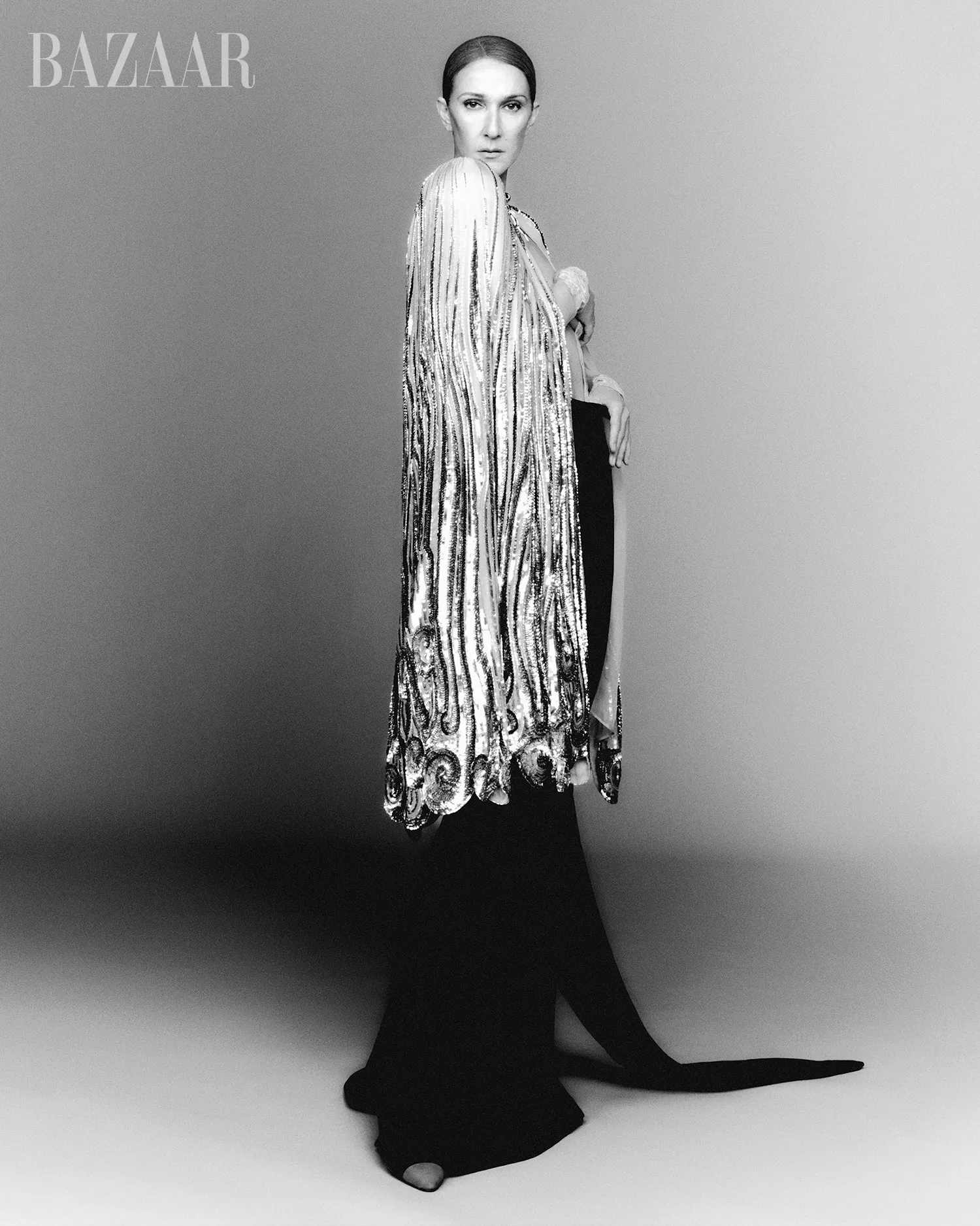Celine Dion in a sequined cape and black dress.