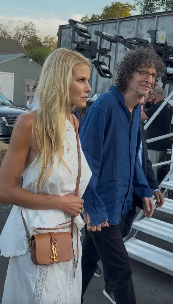 Howard Stern and Beth Ostrosky holding hands and walking together.