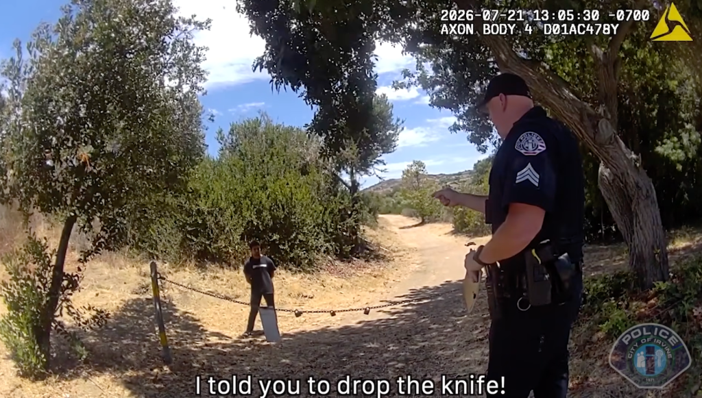 Bodycam footage showing a police officer with a taser drawn, pointing at a man holding a knife in a natural park setting.