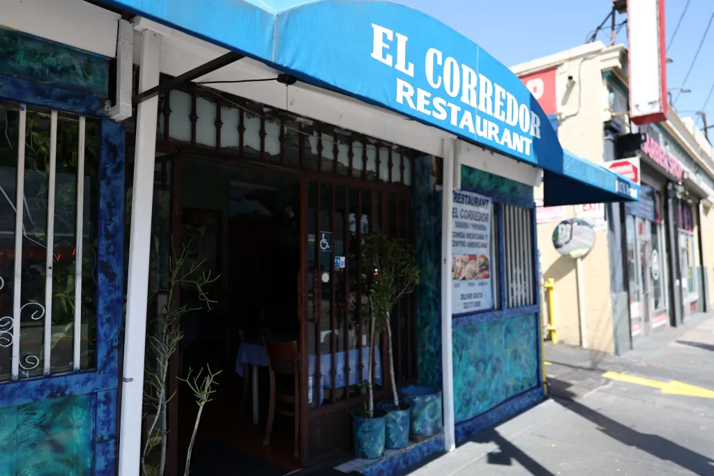Exterior of El Corredor restaurant with a blue awning and storefront sign on S Vermont in Los Angeles.