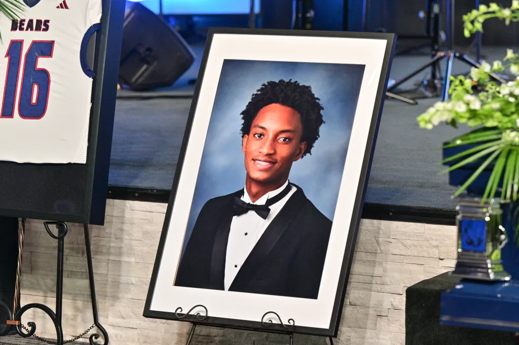 A framed portrait of Nolan Wells at his funeral, next to a white jersey with 