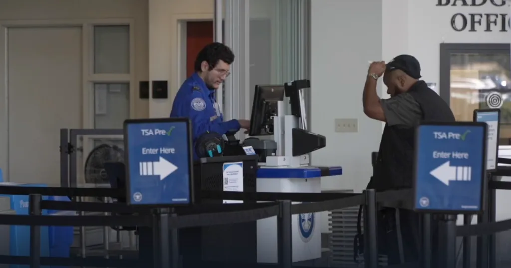 A TSA agent assisting a traveler at a TSA PreCheck counter.