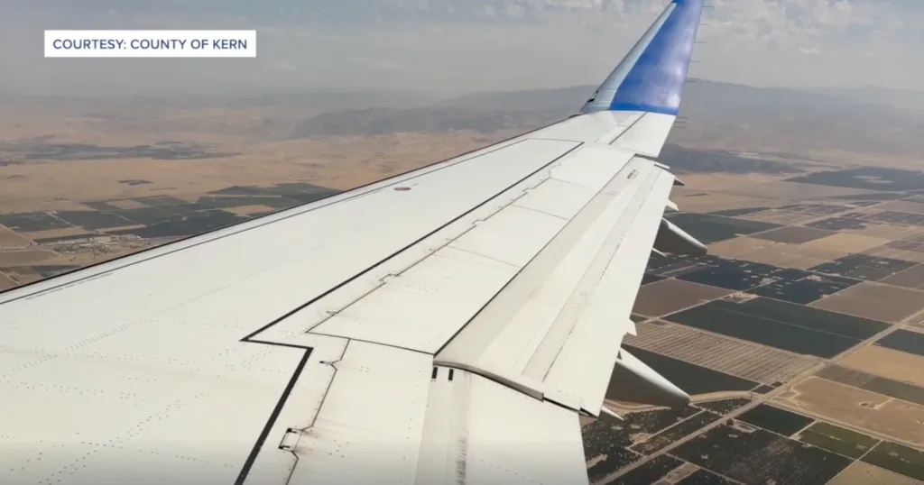 Airplane wing over Bakersfield fields.
