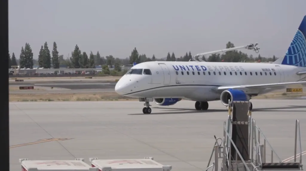 A United Express plane on the tarmac with a crew member attending to it.