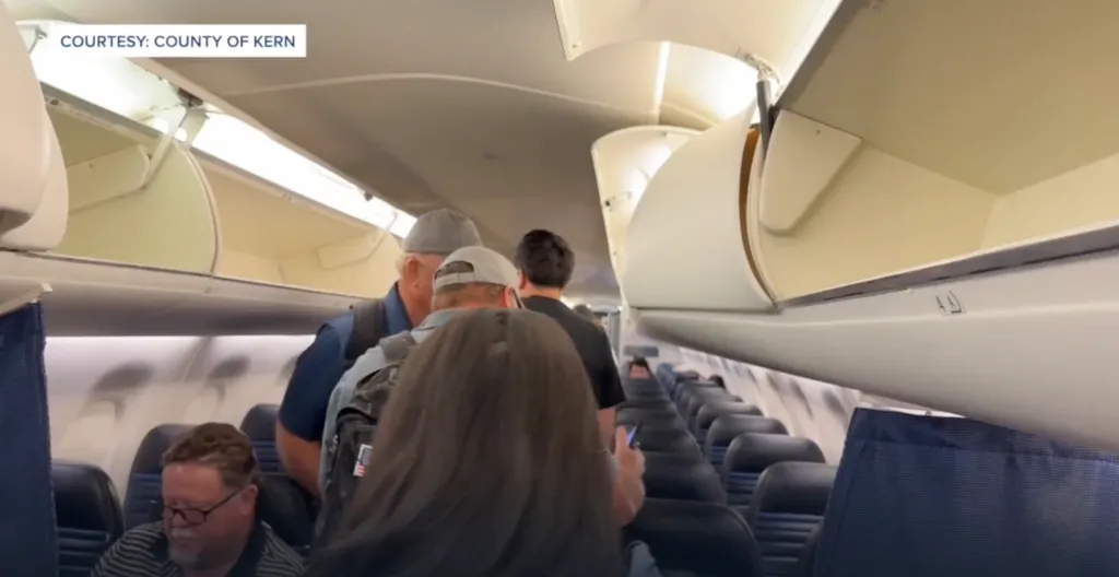 Passengers boarding an airplane with open overhead bins.