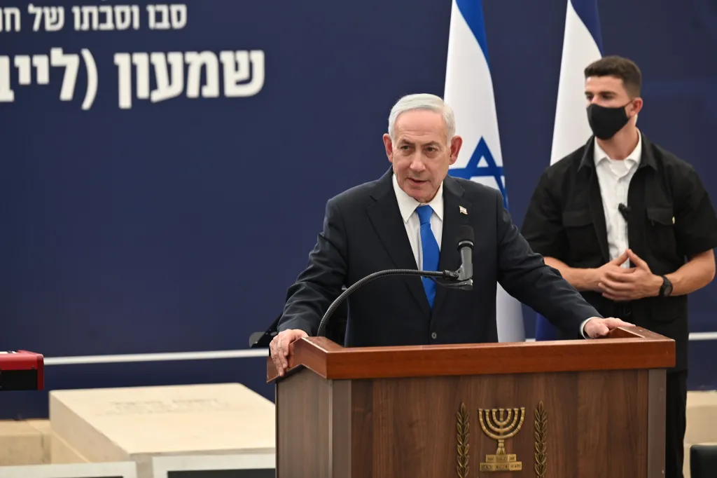 Israeli Prime Minister Benjamin Netanyahu speaks at a podium with the Israeli flag behind him.